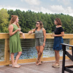 three women standing on the deck holding a beverage
